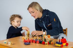 Een kinderfysiotherapeute van Medifit Oss helpt een kind bij het opstapelen van blokjes