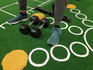 je ziet mannelijke benen op kunstgras met fitness dumbells