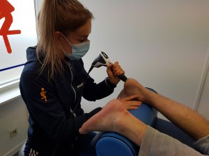 Een fysiotherapeute die shockwave therapie toepast op de onderkant van de voet van haar patiënt.