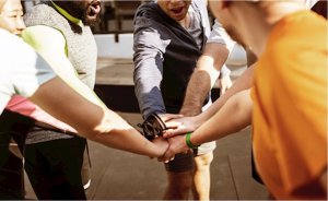 Een groep sportieve mensen slaan de handen op elkaar en juigen